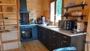 Une cuisine compacte équipée d’une cuisinière, d’un four, d’un four à micro-ondes et d’un petit coin repas avec une chaise et une table.