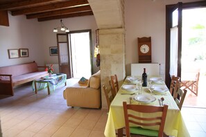 Un comedor con una mesa dispuesta para cuatro personas, un sofá y un reloj en la pared.