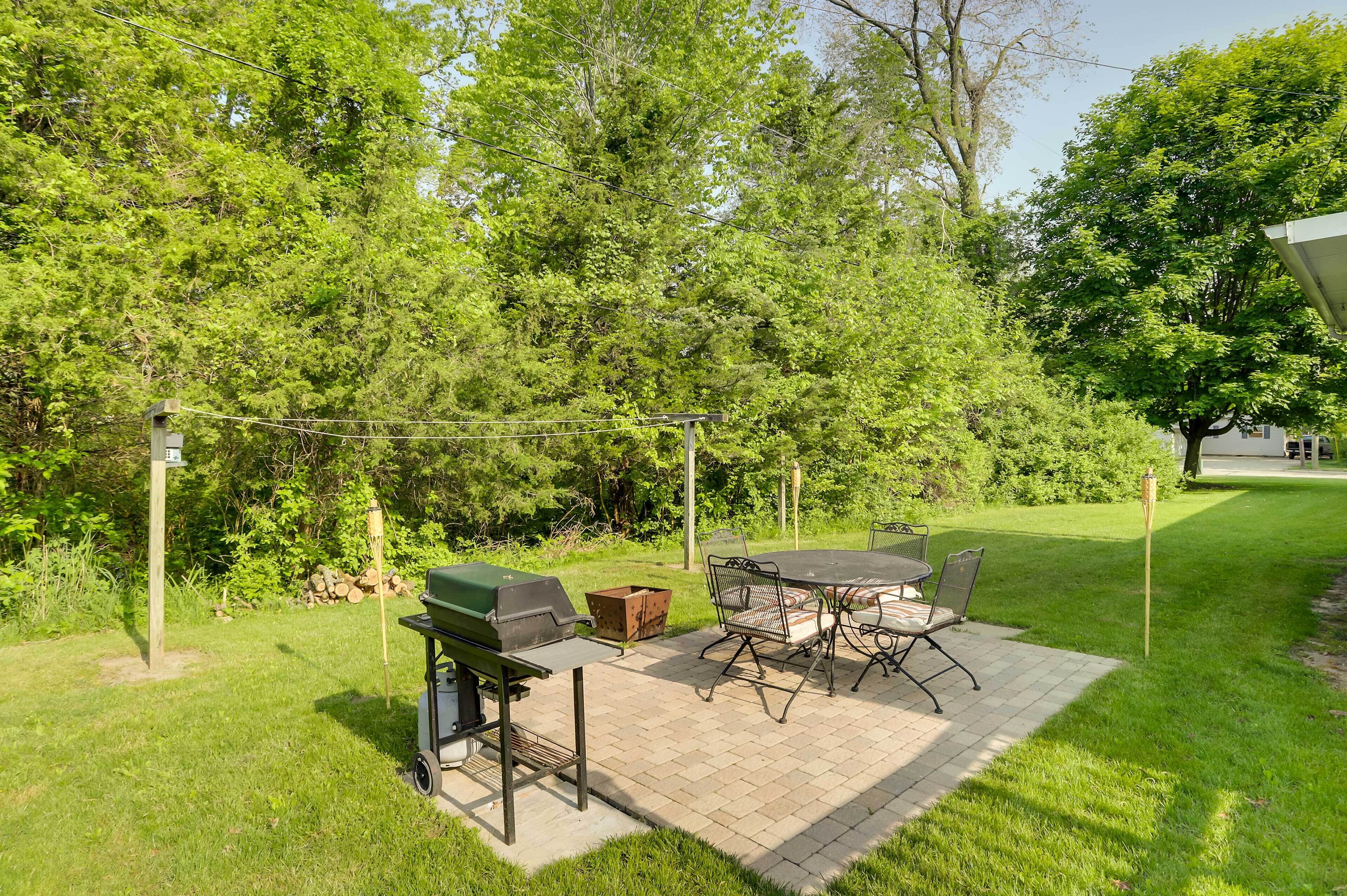 Een terras buiten met een barbecue, tafel en stoelen.