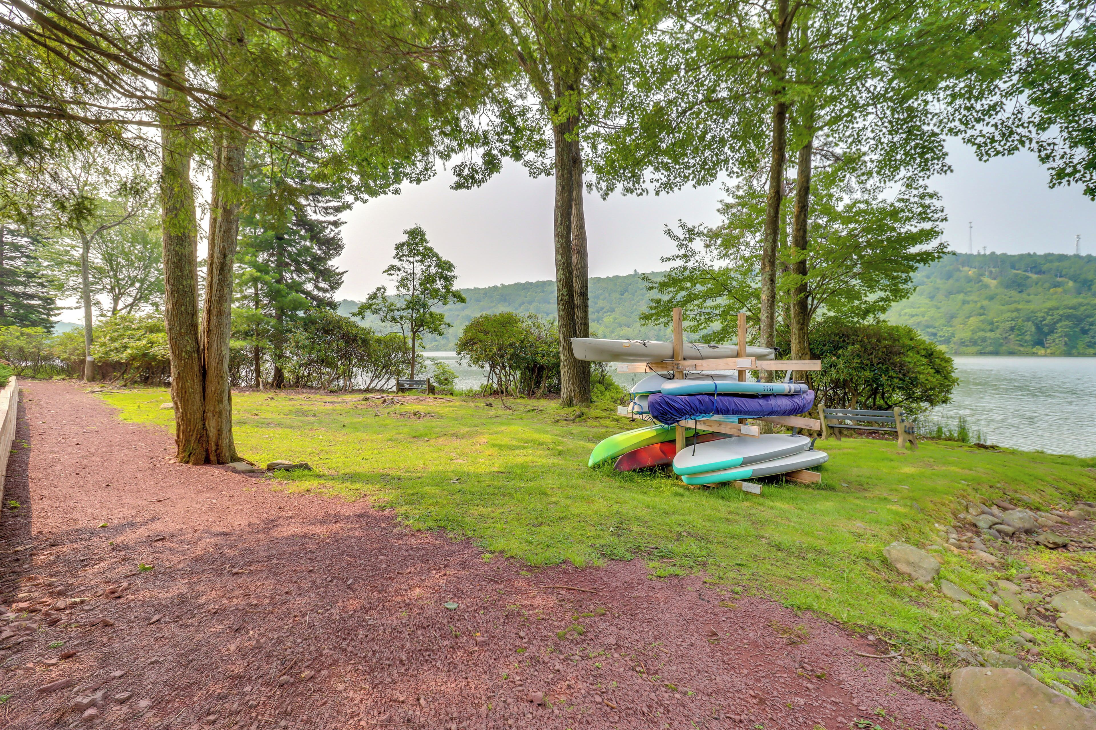 A lakeside path with kayaks and a bench near the water.