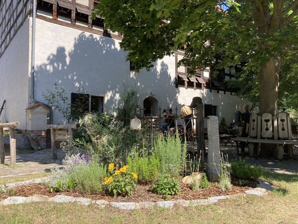 A courtyard with a garden, a wooden fence, and a building with a white facade and wooden beams. - Loft with a fireplace and 2 terraces on a natural lot in Straupitz-Spreewald (Straupitz)