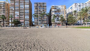 A beachfront with high-rise buildings, palm trees, and a sandy beach.
