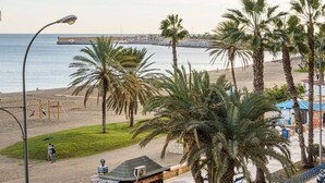 A beachside view with palm trees, a playground, and a pier in the background.