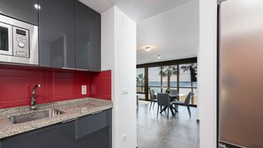 A modern kitchen with a granite countertop, stainless steel appliances, and a red backsplash.