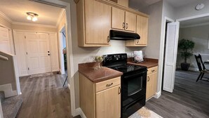 Een moderne keuken met houten kasten, een zwarte kookplaat en een granieten aanrecht.
