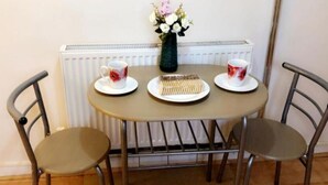 Une table ronde avec deux chaises, un vase de fleurs et deux tasses avec leurs soucoupes.
