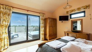 A bedroom with a large bed, a wooden wardrobe, a television, and a view of a hot tub through a sliding glass door. - Buttercup lodge - sleeps 4/5 with hot tub & countryside views (Cheddar)