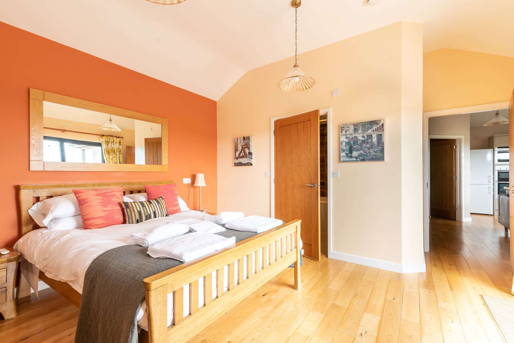 A bedroom with a wooden bed, a large mirror, and a door leading to a hallway.