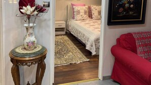 A bedroom with a bed, a nightstand, a globe, a framed painting, and a red sofa. - Apartment T LUXE (Pierrefitte-sur-Seine)
