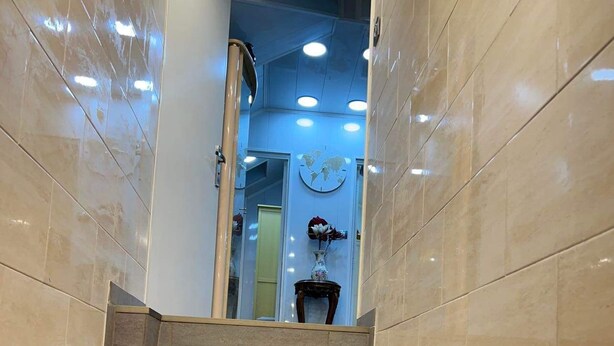 A set of beige-tiled stairs leading to a room with a world map on the wall and a vase with flowers. - Apartment T LUXE (Pierrefitte-sur-Seine)