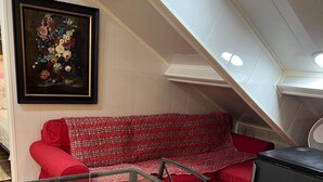 A dining area with a glass table, red upholstered sofa, and a painting on the wall. - Apartment T LUXE (Pierrefitte-sur-Seine)