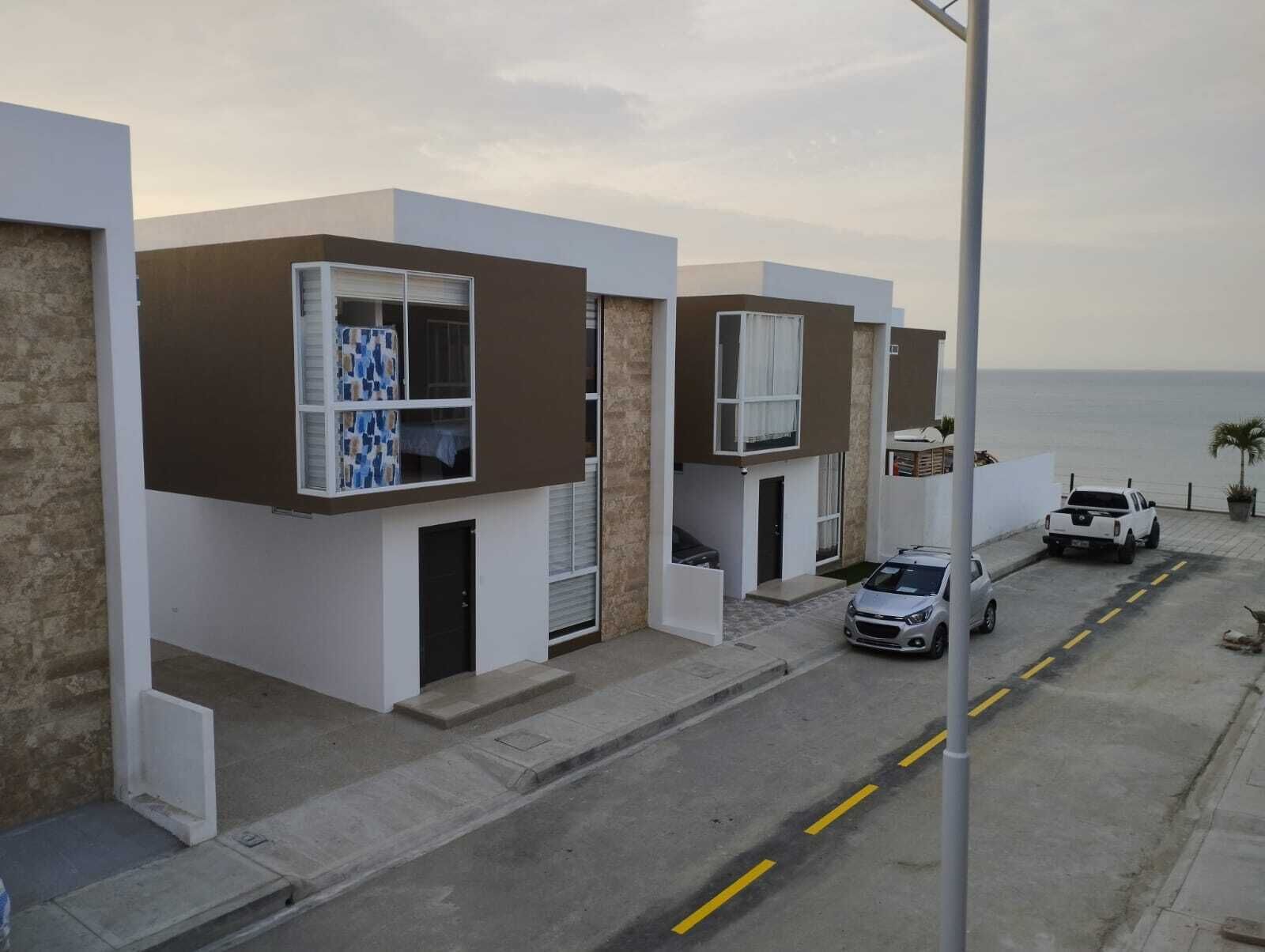 Una strada residenziale moderna con case contemporanee, vista chiara sull'oceano e un furgone bianco parcheggiato.