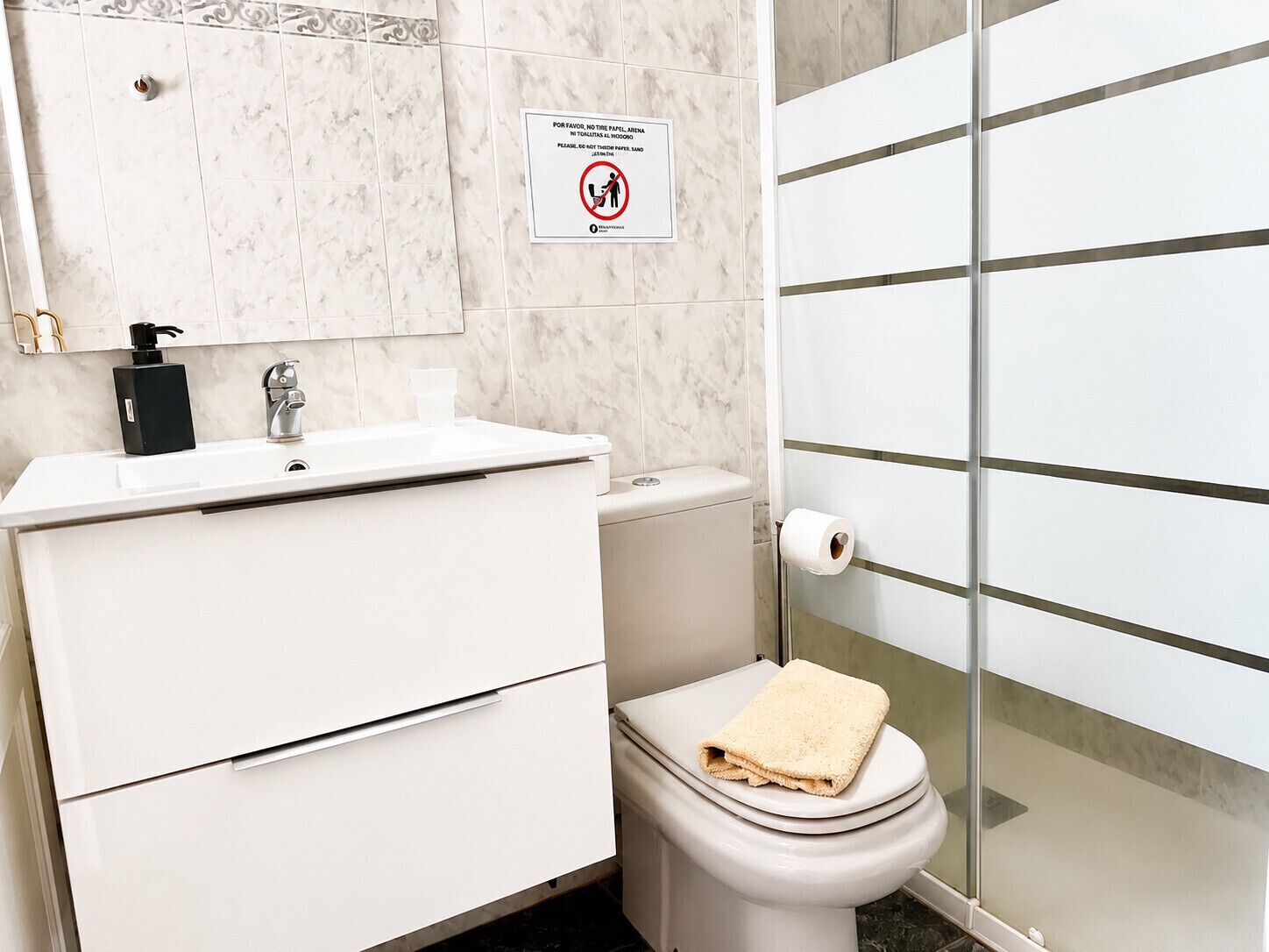 Ein Badezimmer mit Toilette, Waschbecken und einem Schild, das die Verwendung von Papierhandtüchern untersagt.