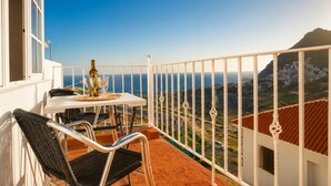 A balcony with a table and chairs, overlooking a coastal view with buildings and a mountain. - Nue Apartment · Terrace & Views Near Las Teresitas (Santa Cruz de Tenerife)