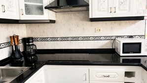 A kitchen with white cabinets, a black countertop, a coffee maker, and a microwave. - Nue Apartment · Terrace & Views Near Las Teresitas (Santa Cruz de Tenerife)