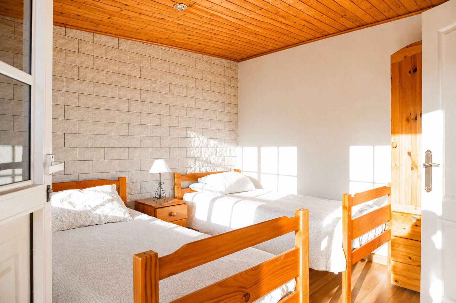 Un dormitorio con dos camas de madera, una pared de ladrillo y techo de madera.