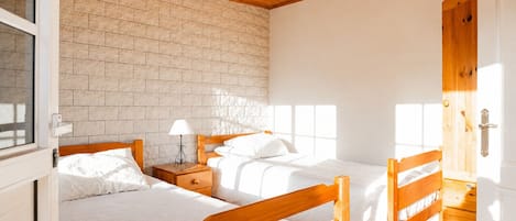 Ein Schlafzimmer mit zwei Holzbettgestellen, einer Ziegelwand und einer Holzbalkendecke.