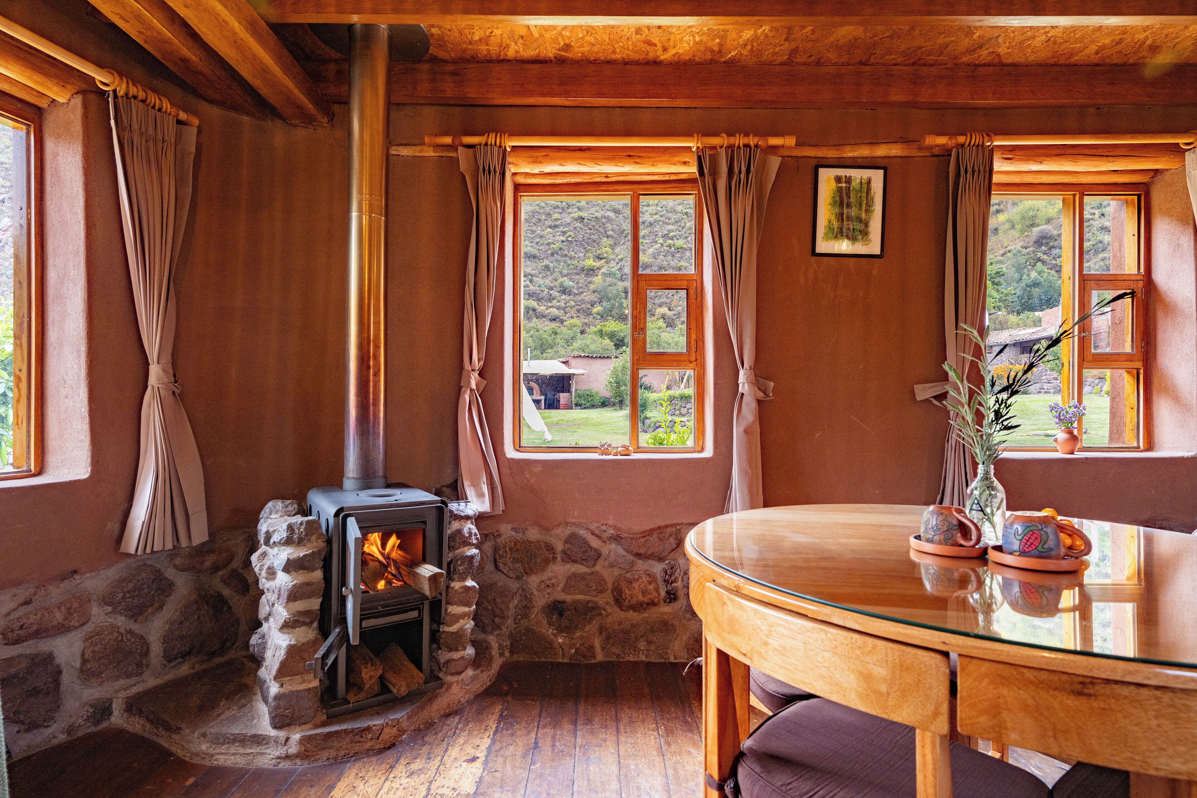 A cozy room with a stone fireplace, wooden walls, and a glass table.