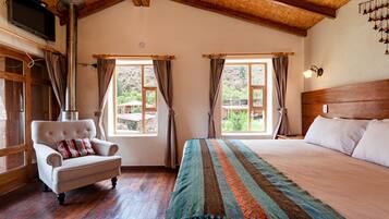 A bedroom with a large bed, a wooden headboard, a chair with a cushion, and a window with curtains.