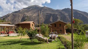 A house with a garden, a hammock, and a mountain in the background.