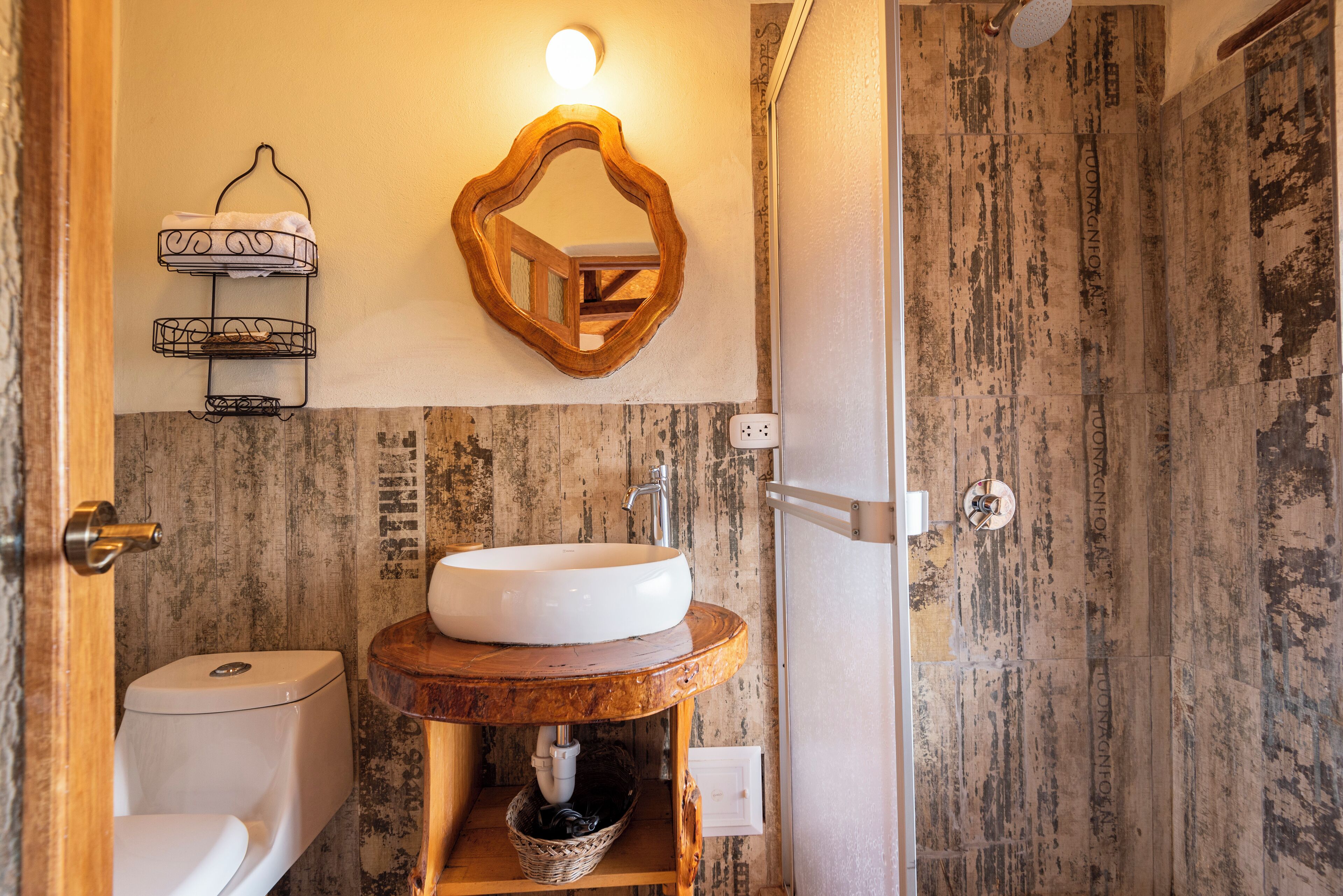 Un baño con diseño rústico, que incluye un tocador de madera con lavabo, un inodoro y un espejo decorativo.