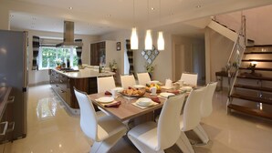 A modern dining area with a central island, white chairs, and a staircase. - Solway (Chester)