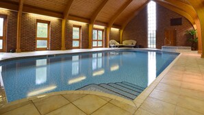 An indoor swimming pool with a high wooden ceiling, brick walls, and a bench along one side. - Solway (Chester)
