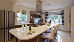 A modern kitchen with a central island, stainless steel appliances, and a large window providing natural light. - Solway (Chester)