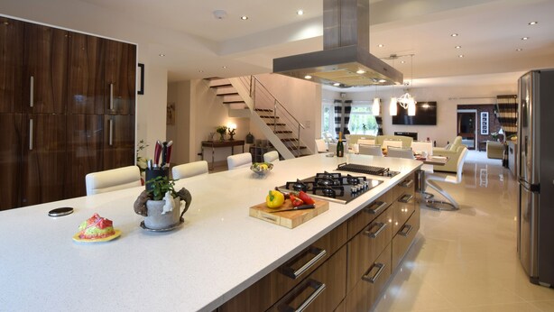 A modern kitchen with a large island, stainless steel appliances, and a staircase leading to another level. - Solway (Chester)
