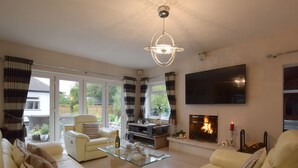 A spacious living room with a fireplace, comfortable seating, a glass coffee table, and a large flat-screen TV. - Solway (Chester)