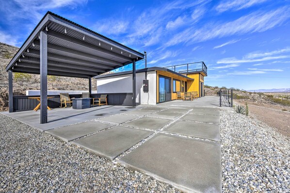 Een modern gebouw met een overdekte patio, zitplaatsen buiten en een helder uitzicht op het omliggende landschap.