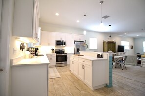 Une cuisine moderne avec des meubles blancs, des appareils en acier inoxydable et un îlot central.
