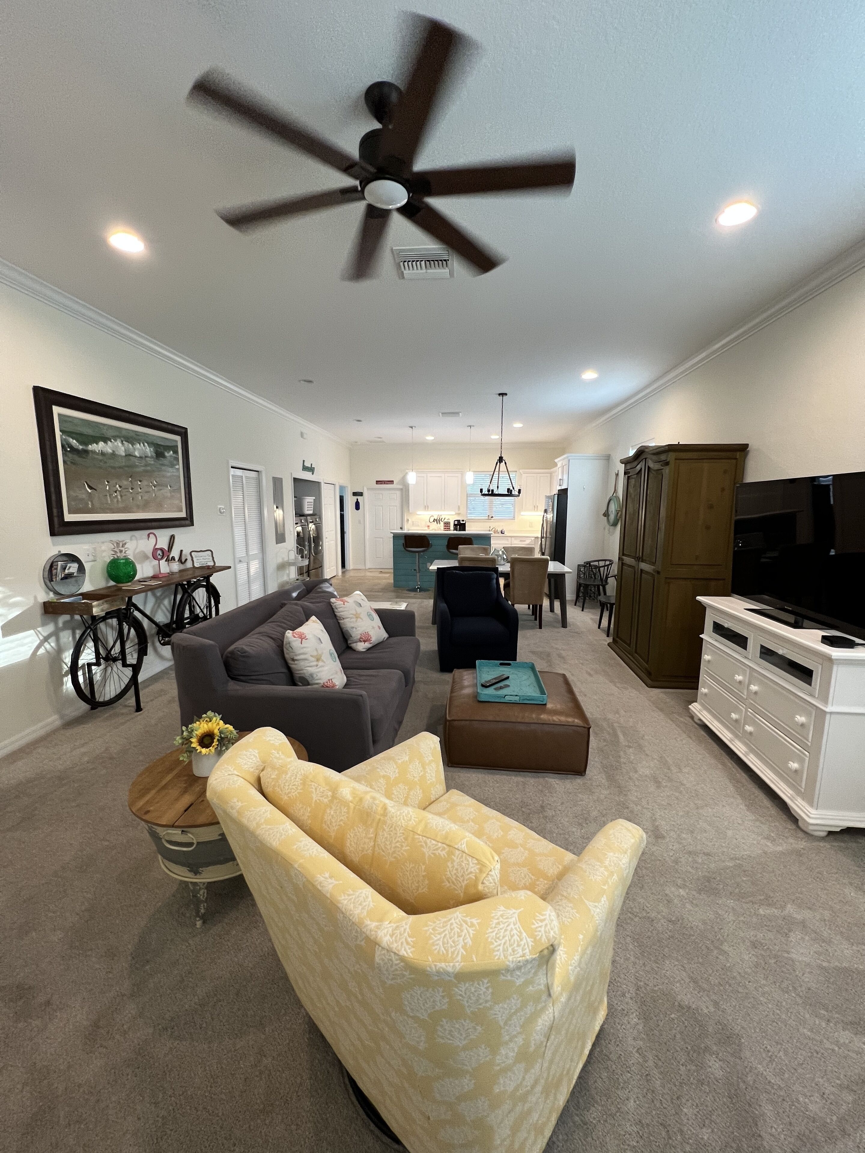 A living room with a ceiling fan, a sofa, a chair, a coffee table, and a TV stand.