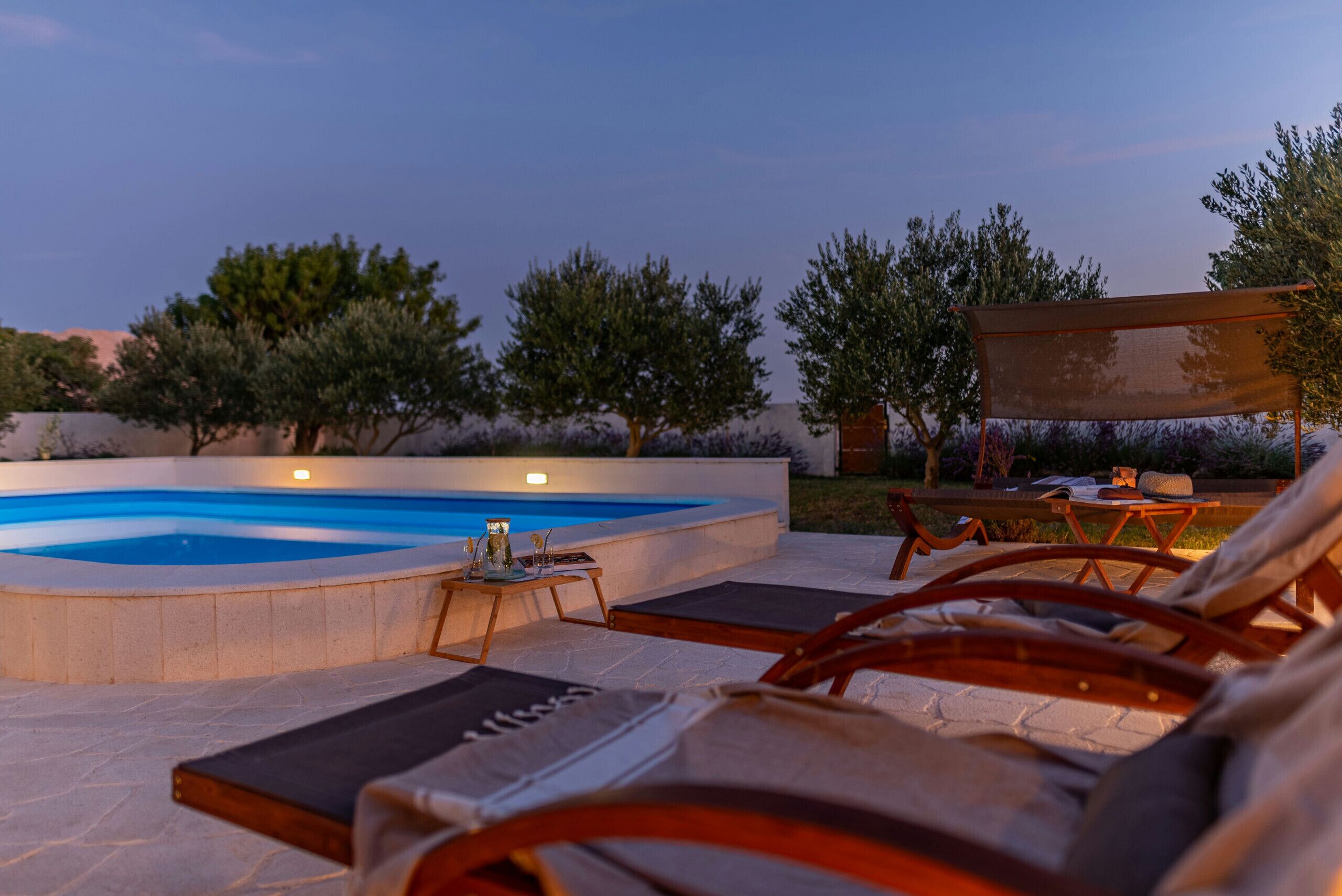 A poolside area with lounge chairs, a table with a drink, and a pergola.