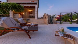 Una villa con piscina, mobiliario exterior y una escalera de piedra que lleva a la entrada.
