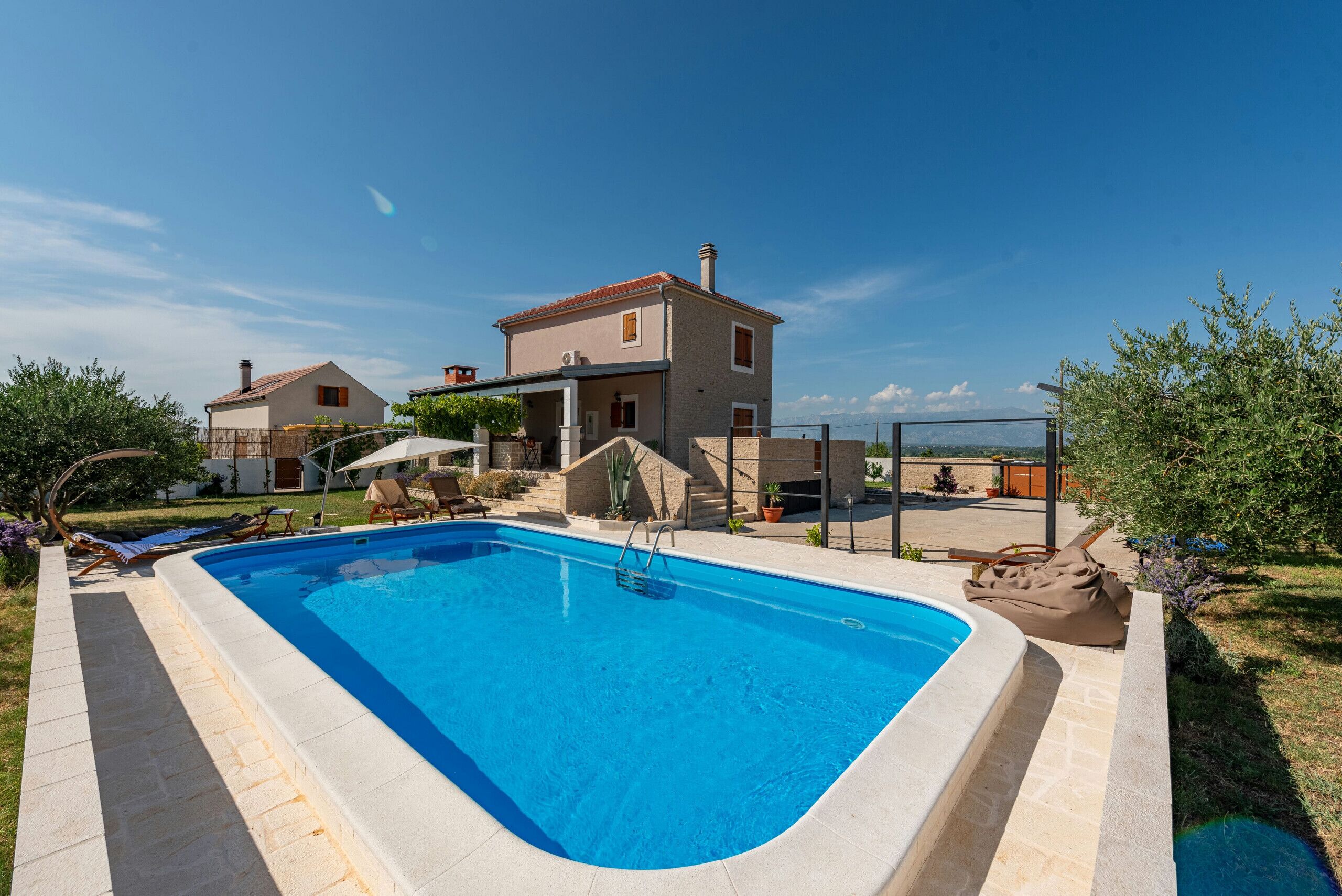 Une piscine rectangulaire à l’eau d’un bleu limpide, entourée d’une terrasse en pierre.