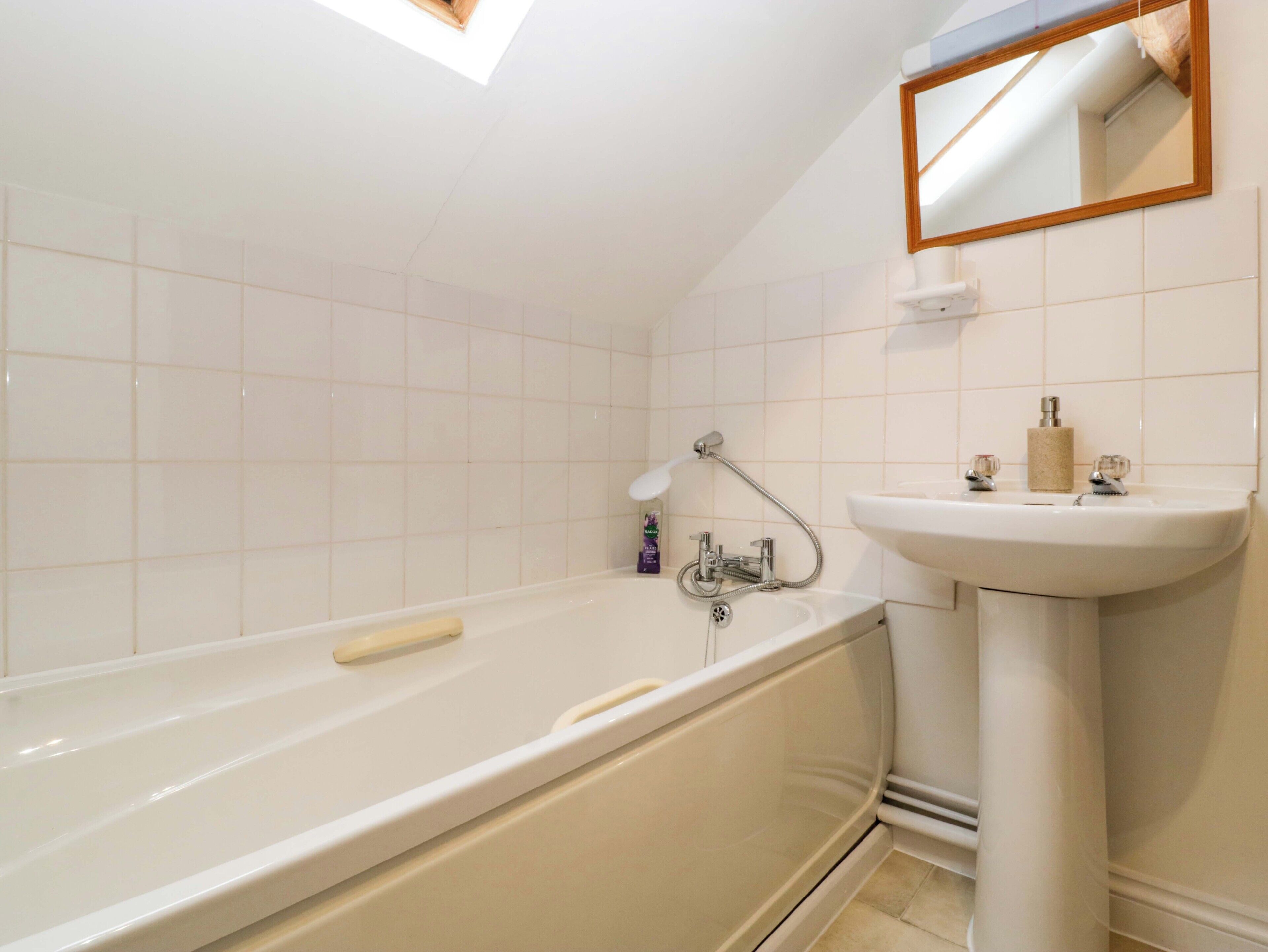 A bathroom with a bathtub, a sink, and a mirror.