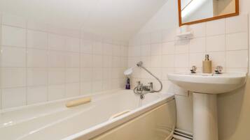 A bathroom with a bathtub, a sink, and a mirror.