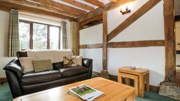Una sala de estar acogedora con un sofá de cuero, una mesa de centro de madera y una chimenea de piedra.
