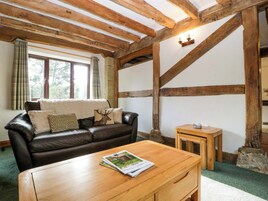 Una sala de estar acogedora con un sofá de cuero, una mesa de centro de madera y una chimenea de piedra.