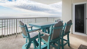 Un balcon avec une table et des chaises, donnant sur l’océan.