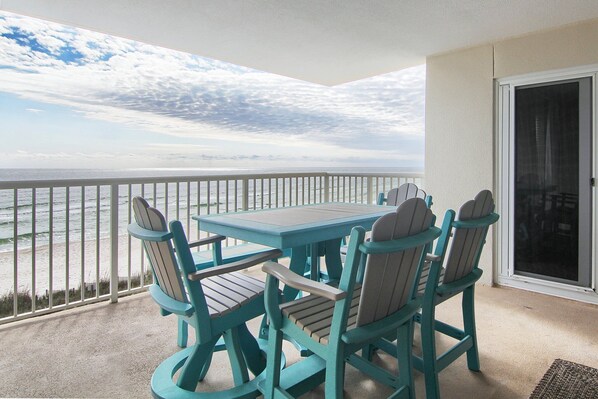 A balcony with a table and chairs, overlooking the ocean.