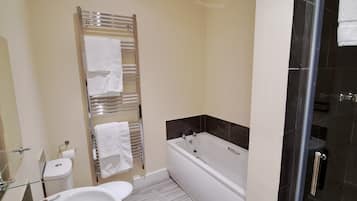 A modern bathroom with a glass shower enclosure, a white bathtub, and a glass-enclosed toilet.