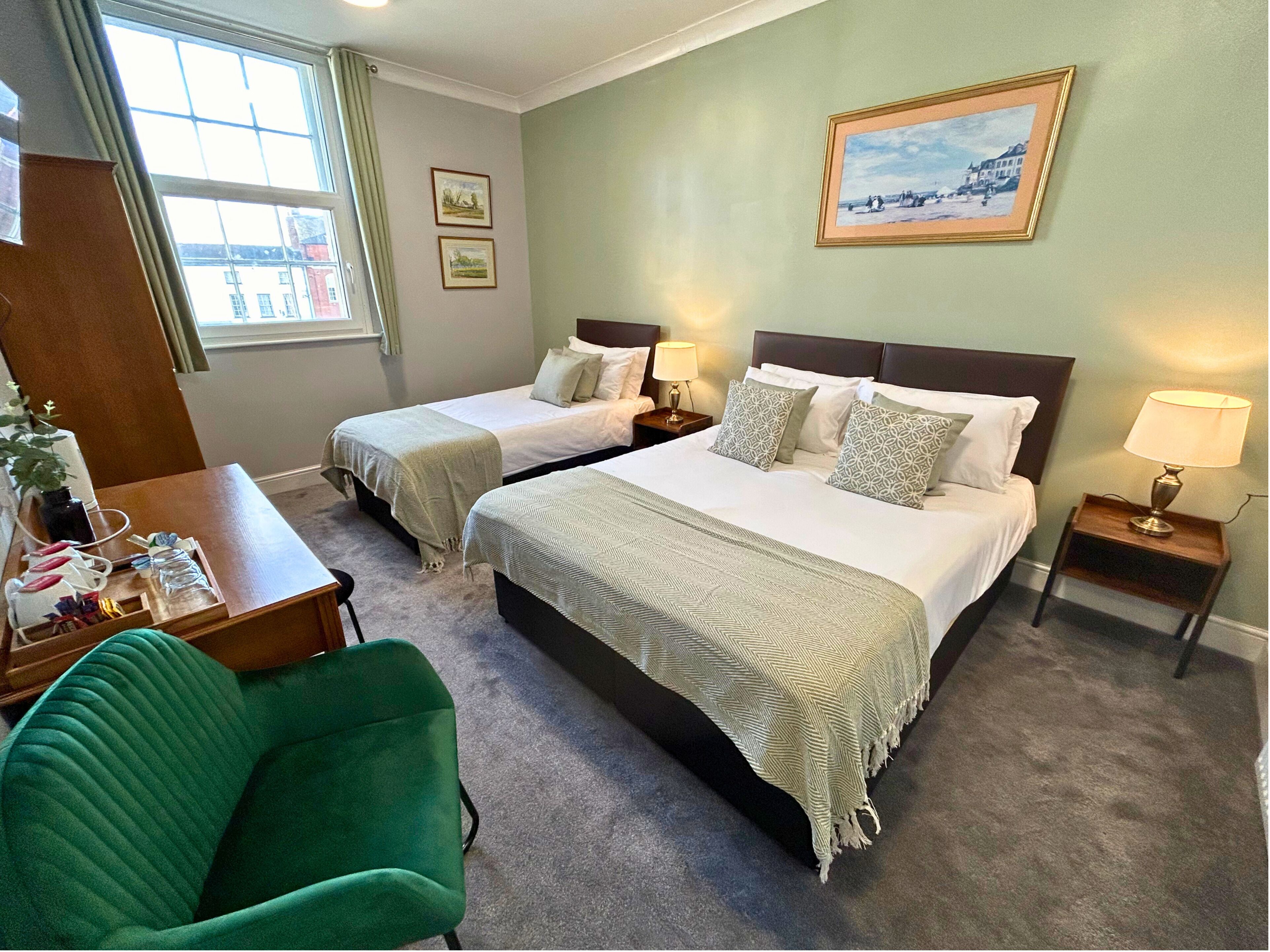 Une chambre d’hôtel avec deux lits, un bureau, une chaise et une fenêtre.