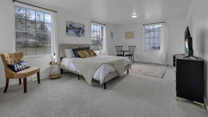 A bedroom with a bed, a chair, a desk, and a TV. - Spacious, Modern, Healing Home in Columbus (Columbus)
