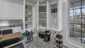 A kitchen with white cabinets, a countertop with a coffee maker, toaster, and spice rack. - Spacious, Modern, Healing Home in Columbus (Columbus)