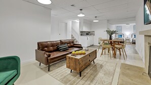 A modern living room with a leather sofa, wooden coffee table, and a dining area with chairs and a table. - Spacious, Modern, Healing Home in Columbus (Columbus)