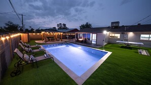 Un giardino con piscina, prato sintetico verde e area relax all'aperto.