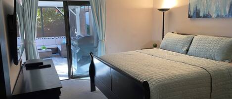 Un dormitori amb llit, escriptori, ventilador de sostre i vista a l'exterior a través d'una porta corredissa.