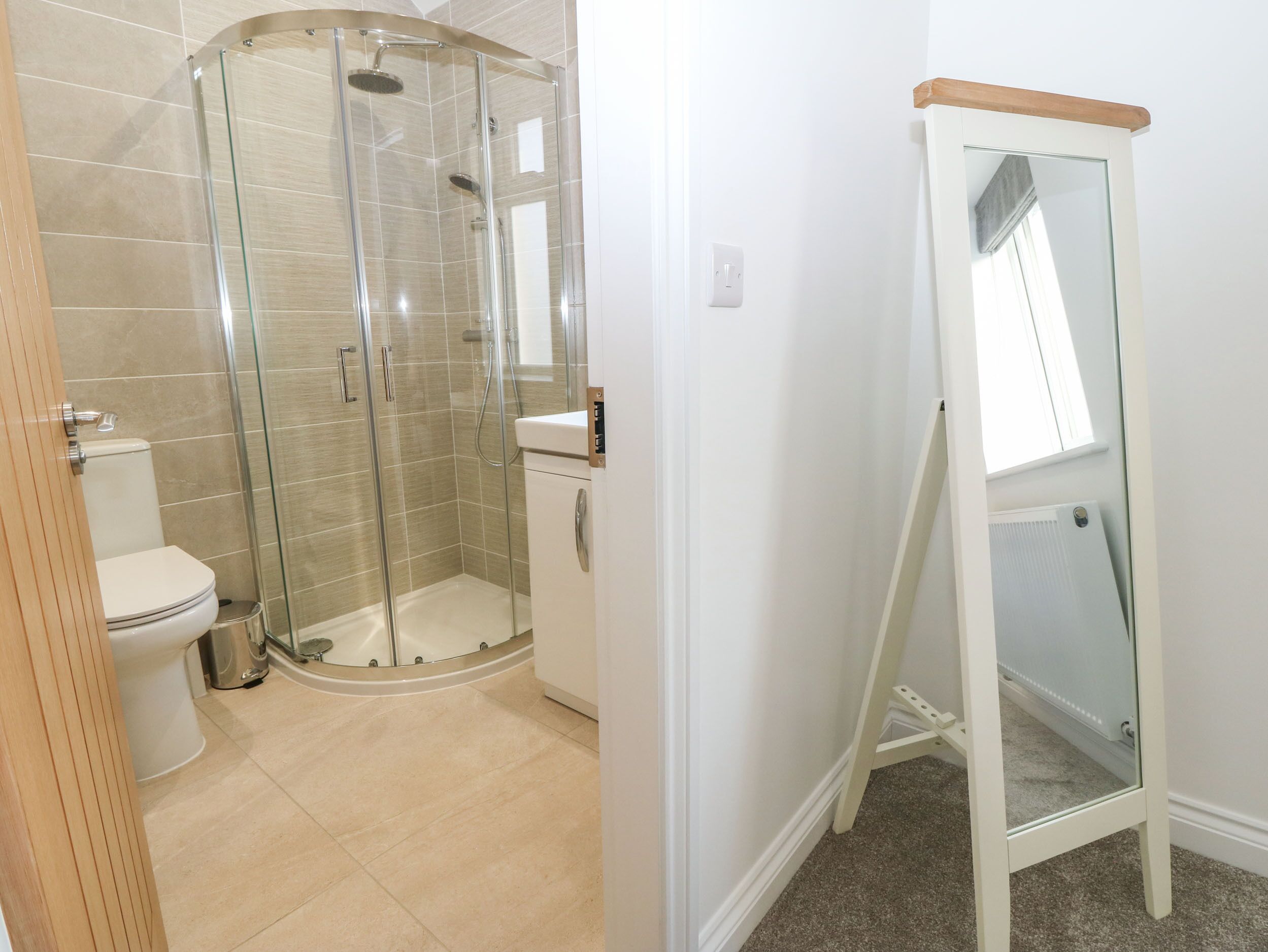 A bathroom with a glass-enclosed shower, a toilet, and a sink.